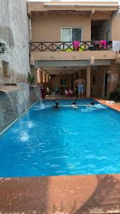 a large swimming pool with a waterfall in front of a house at Bungalows villas belen in Cedro