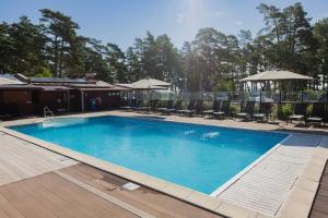 a large blue swimming pool with chairs and umbrellas at Pensionat Lövängen, Ljugarn in Ljugarn