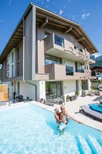 two people in a swimming pool in front of a house at Enjoy The Alps in Flachau