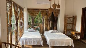 two beds in a room with a window at Hostal Axlan in Puerto Escondido