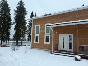 una casa in legno con la neve di fronte di Villa Siltasaari a Sotkamo