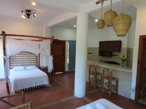 a bedroom with a bed and a kitchen in a room at Hostal Axlan in Puerto Escondido