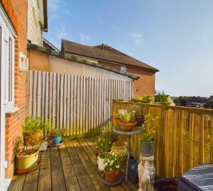 a patio with potted plants on a wooden deck at Modern Hastings Home for Groups with Garden Terrace and Dedicated Workspace in Hastings