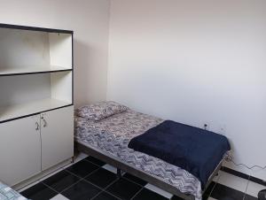 ein kleines Schlafzimmer mit einem Bett und einem Regal in der Unterkunft Hospedagem próxima ao centro apto simples in Feira de Santana