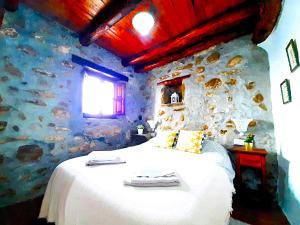 Un dormitorio con una cama con una pared de piedra. en Petit Nazari, en Benaocaz 7 fotos más