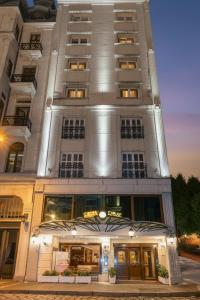 a tall white building with a sign on it at Taksim Pera Rose Hotel & Spa - Istiklal Street in Istanbul