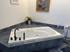 Saint-AntoninMaison d edouard的浴室里有一个大浴缸，旁边放着一瓶鲜花。