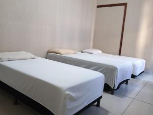 due letti in una stanza con lenzuola bianche di Hotel luxus d cor a Porto Ferreira