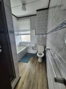 a bathroom with a toilet and a bath tub at Jakaranda Holiday Flat in Uvongo Beach +5 photos