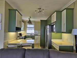 a kitchen with green cabinets and a couch at Jakaranda Holiday Flat in Uvongo Beach