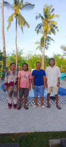 吉利美诺AMIGOS BUNGALOWS GILI MENO的一群男人站在棕榈树前