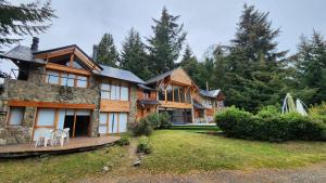 a large house with two chairs on a yard at Casa Del Bosque Aparts in Villa La Angostura