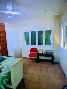 a room with a table and a red chair and windows at La Casona Hostel in Bermejo