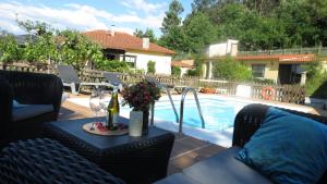 a patio with a table with wine glasses and a pool at Casa Rural Pontevedra con piscinajardínbarbacoa in Pontevedra