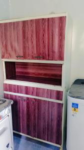 czerwona drewniana szafka w kuchni z lodówką w obiekcie شقه بنزله عبد اللاه باسيوط w mieście Nazlat ‘Abd Allāh