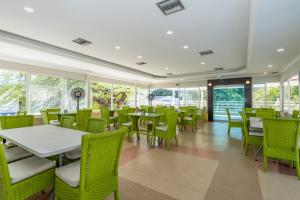 a restaurant with green chairs and tables and windows at Hotel Arhuaco Rodadero in Santa Marta