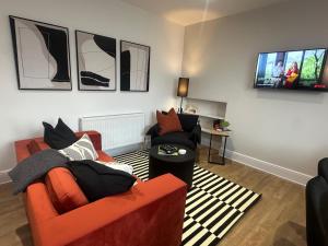 a living room with an orange couch and a flat screen tv at Gorgeous Town Centre 3-Bed 2-Bath Apartment Parking Available in Harrogate