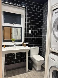 a bathroom with a toilet and a sink and a window at Gorgeous Town Centre 3-Bed 2-Bath Apartment Parking Available in Harrogate