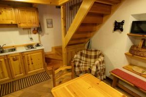 a kitchen with wooden cabinets and a table and a staircase at La Casetta del Picchio in Caspoggio