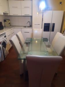 eine Küche mit Glastisch und weißen Schränken in der Unterkunft AlexandraMihai in Craiova