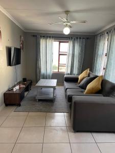 a living room with a couch and a table at Blossom on 13 in Gqeberha +2 photos