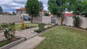 a yard with a fence and a house at Nkwe Guesthouse in Roodepoort
