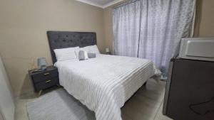 a bedroom with a bed with a white comforter and a television at Nkwe Guesthouse in Roodepoort +8 photos