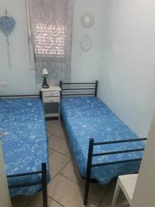 丽都玛里尼Casa Azzurra的一间卧室，有两张床、一张书桌和一扇窗户