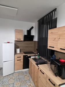 a kitchen with wooden cabinets and a white refrigerator at Apartament klimatyczny in Piece +22 photos