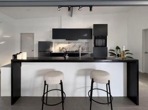 a kitchen with a black counter and two stools at Kalma - 2 Bedroom Villa with Private Pool in Santander