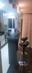 una cucina con bancone nero e 2 sgabelli di Dois Quartos Completo a Vila Velha