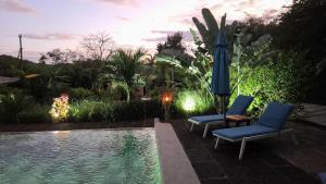Dos sillas y una sombrilla junto a una piscina. en Tee-K Lodge Tamarindo, en Tamarindo 14 fotos más