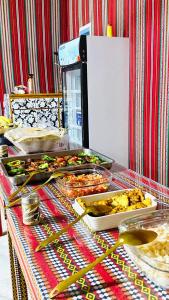 Una mesa con muchas bandejas de comida encima. en Wadi Rum Bubbles Luxury Camp, en Wadi Rum