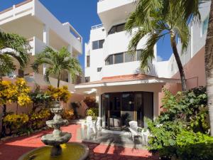 a fountain in front of a building with palm trees at Casa Cuatro Estaciones in Puerto Morelos
