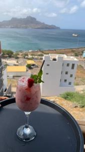 a drink sitting on a table with a view of the ocean at Residencial P&P in Mindelo