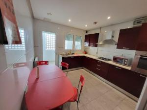 a kitchen with a red table and red chairs at Duplex el 3ebdelleyya en face tennis club la marsa in Tunis
