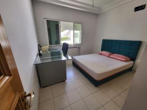a bedroom with a bed and a desk and a window at Duplex el 3ebdelleyya en face tennis club la marsa in Tunis