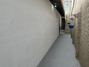 an alley with a white wall and a blue bucket at Casa do Alessandro in Vila Velha