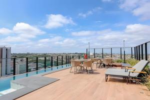 a balcony with tables and chairs on a roof at Stay Pure | Design Clean e Atmosfera Tranquila in Campo Grande