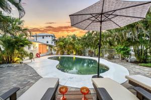 einen Pool mit Sonnenschirm und Bänken in der Unterkunft Casita Sun Star - 1135 in Siesta Key