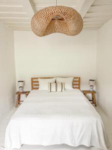 a bedroom with a white bed and a chandelier at Makravölgyi Házikó in Csajág