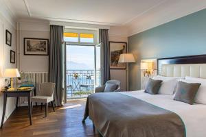 a hotel room with a bed and a desk and a window at Grand Hotel Suisse Majestic, Autograph Collection in Montreux