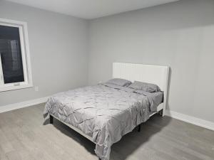 a bed in a white bedroom with a window at Brand new custom 4BR house in Oshawa