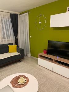 a living room with a large clock on a green wall at Flat in Fushë Kosova in Kosovo Polje