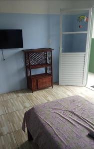 Schlafzimmer mit einem Bett, einem TV und einer Tür in der Unterkunft Pousada Nan in Salvador