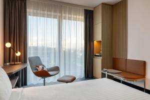 Una habitación de hotel con una cama, una silla y una ventana. en Courtyard by Marriott Bremen, en Bremen 77 fotos más