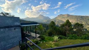 a house with a balcony with mountains in the background at Casa 09 Monte Boa Vista - Refúgio com Piscina Privativa, Sauna e Vista das Montanhas in Teresópolis