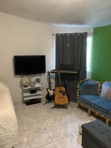 a living room with a guitar and a tv at Apartamento la 20 in Tijuana