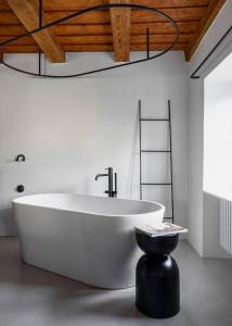 un bagno con una grande vasca bianca e uno sgabello nero di Clementine House a Cesky Krumlov
