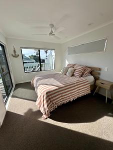 a bedroom with a bed with a striped blanket at Seaside heaven family friendly in Tauranga +15 photos